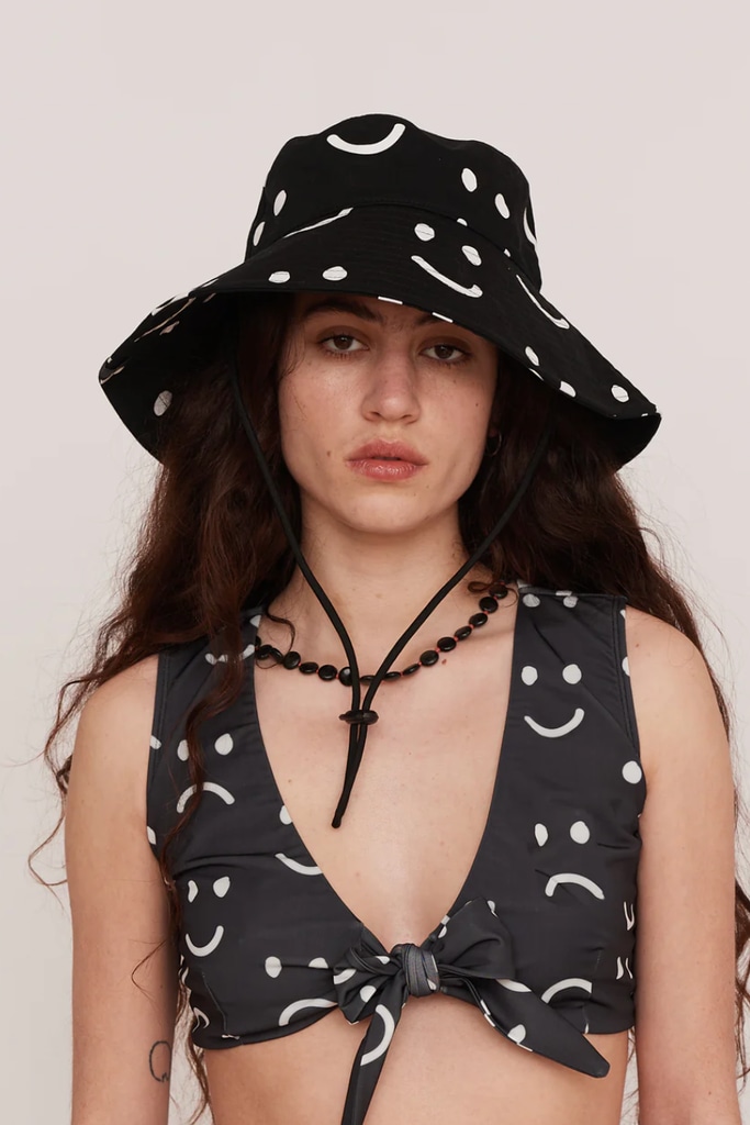 A model poses in a black bucket hat from Lazy Oaf