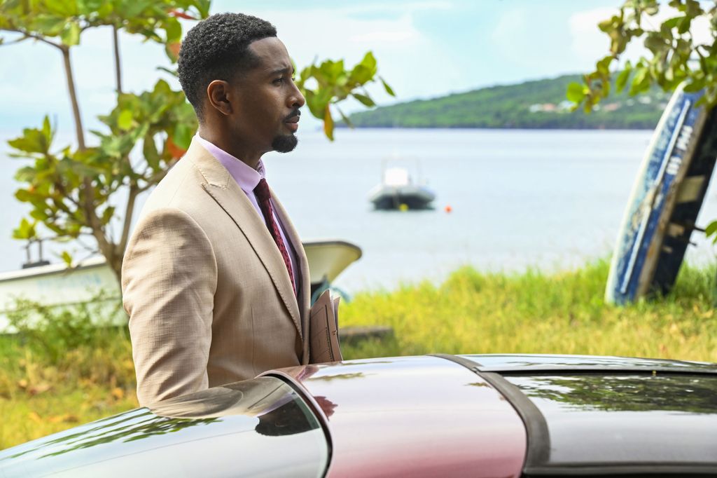 Man in suit standing by sports car