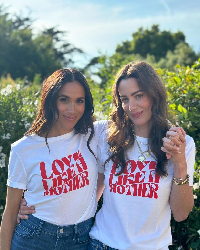Meghan Markle posing with a friend wearing a t-shirt saying 'love like a mother'