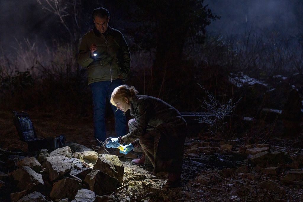 man and woman looking at crime scene in dark 
