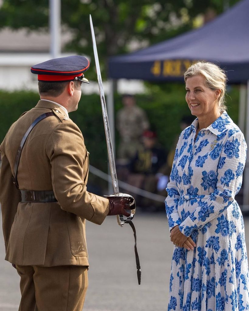Duchess Sophie smiling wearing a blue and white floral dress during military visit in Wiltshire