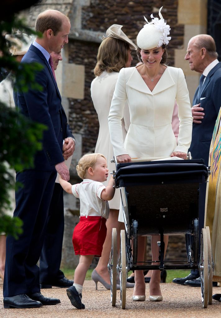 Prince George peers into Princess Charlotte's pram at christening