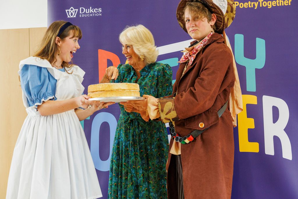 Camilla cut a cake on stage with Alice and the Mad Hatter