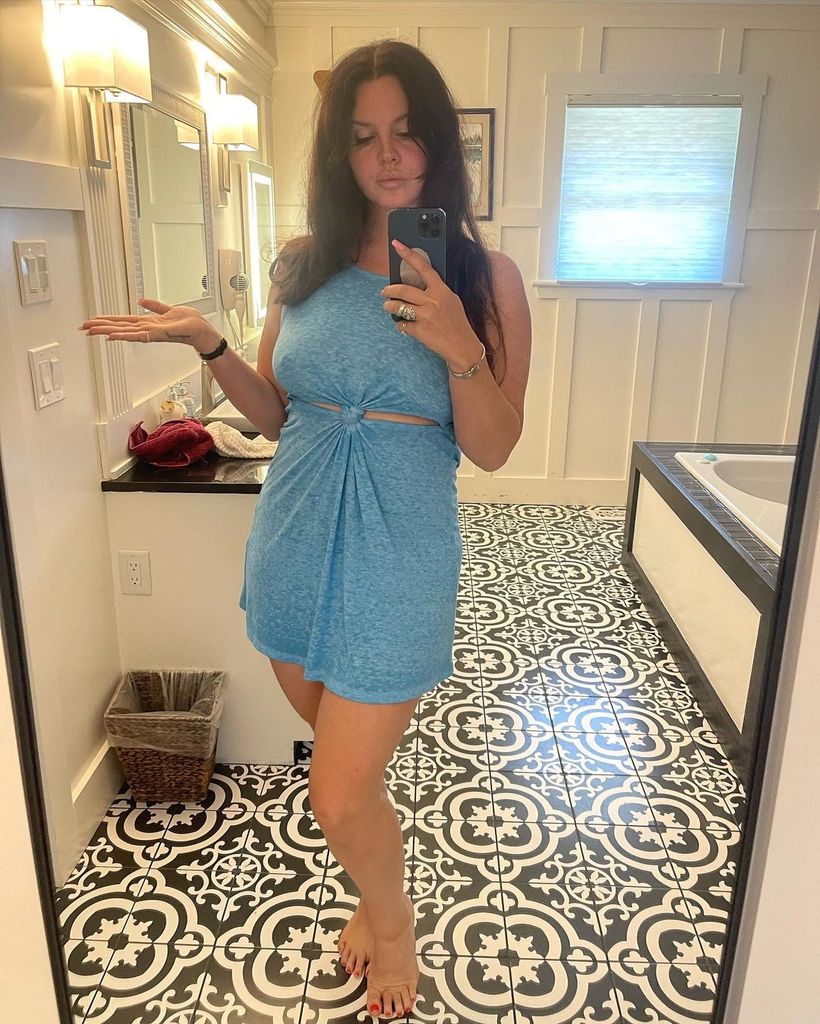 Lana Del Rey in blue knotted dress posing in bathroom