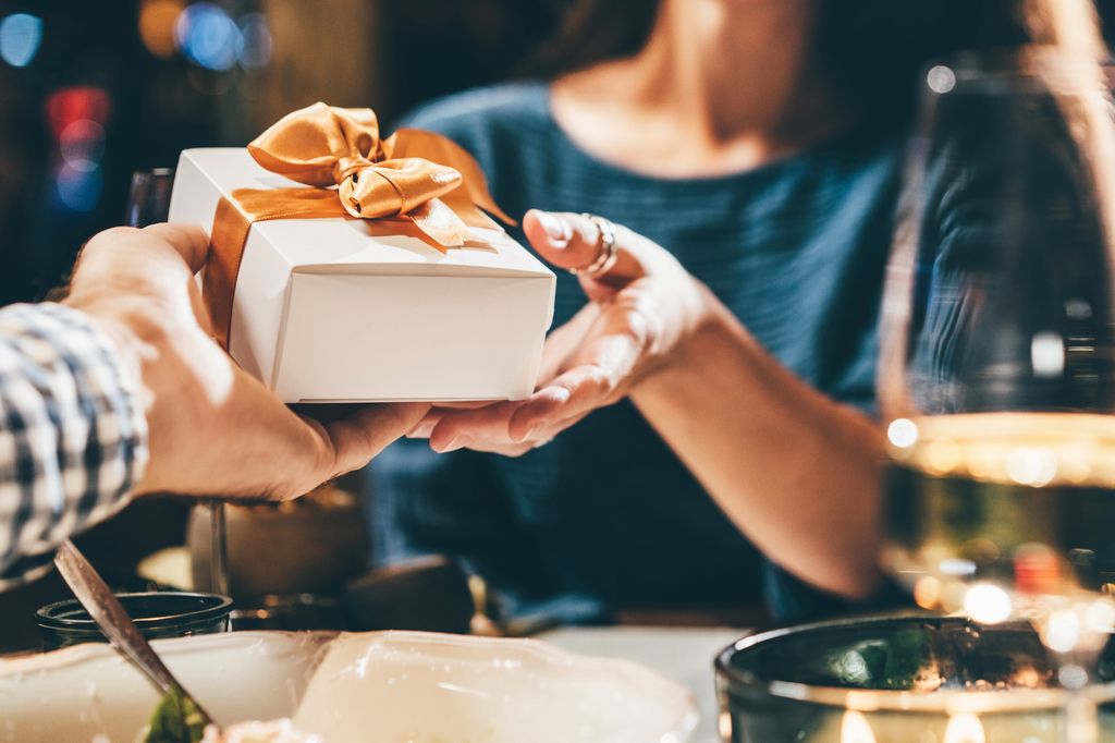 Man giving small gift in restaurant.