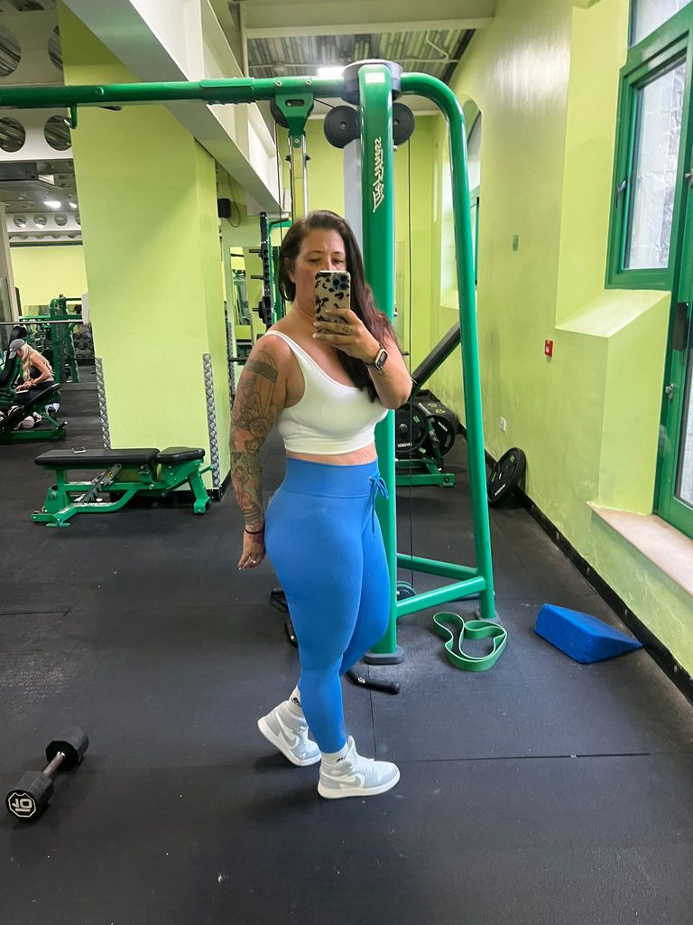 Woman taking a selfie in blue leggings and a white top