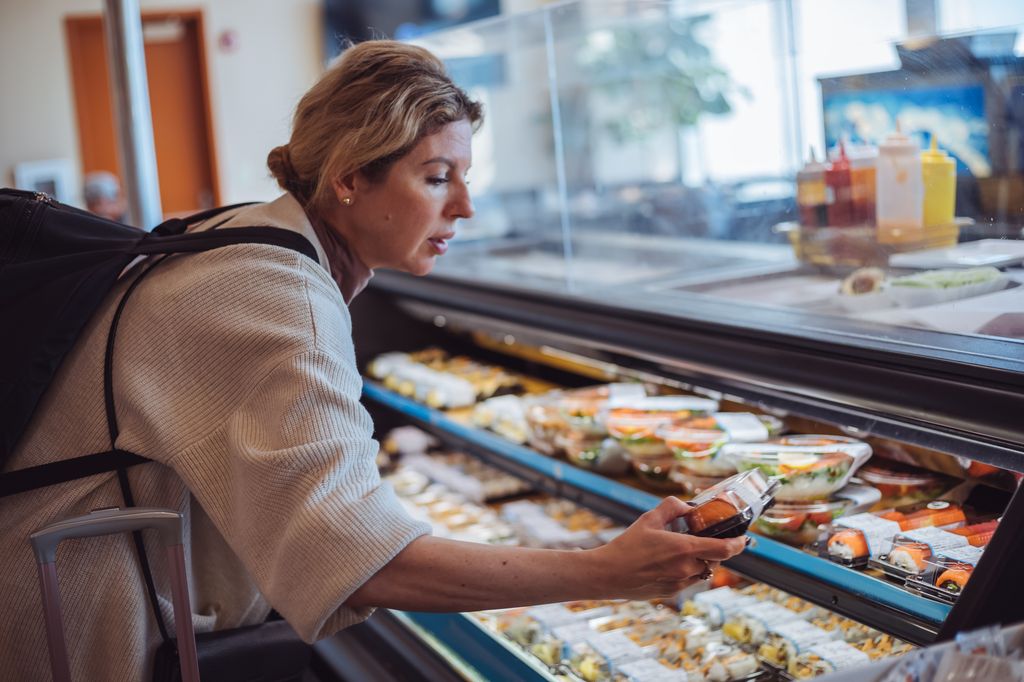 Female tourist with a backpack and suitcase selecting food
