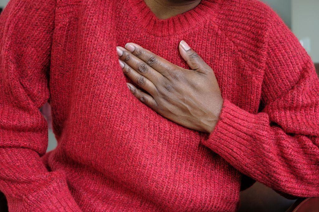 Close-up of unrecognizable black woman holding her chest in pain