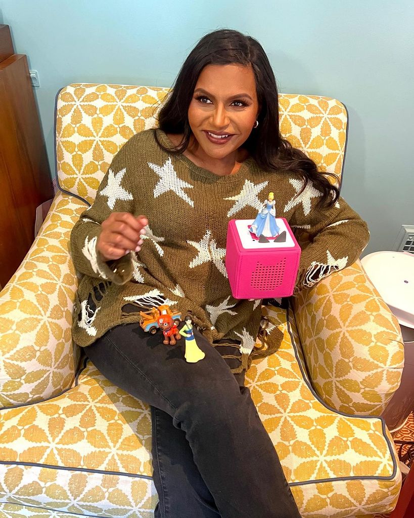 Mindy Kaling sitting in a yellow patterned armchair
