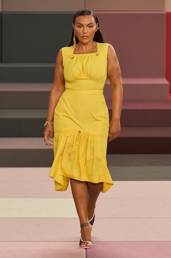 A model wears a bright yellow square neck midi dress and heels 