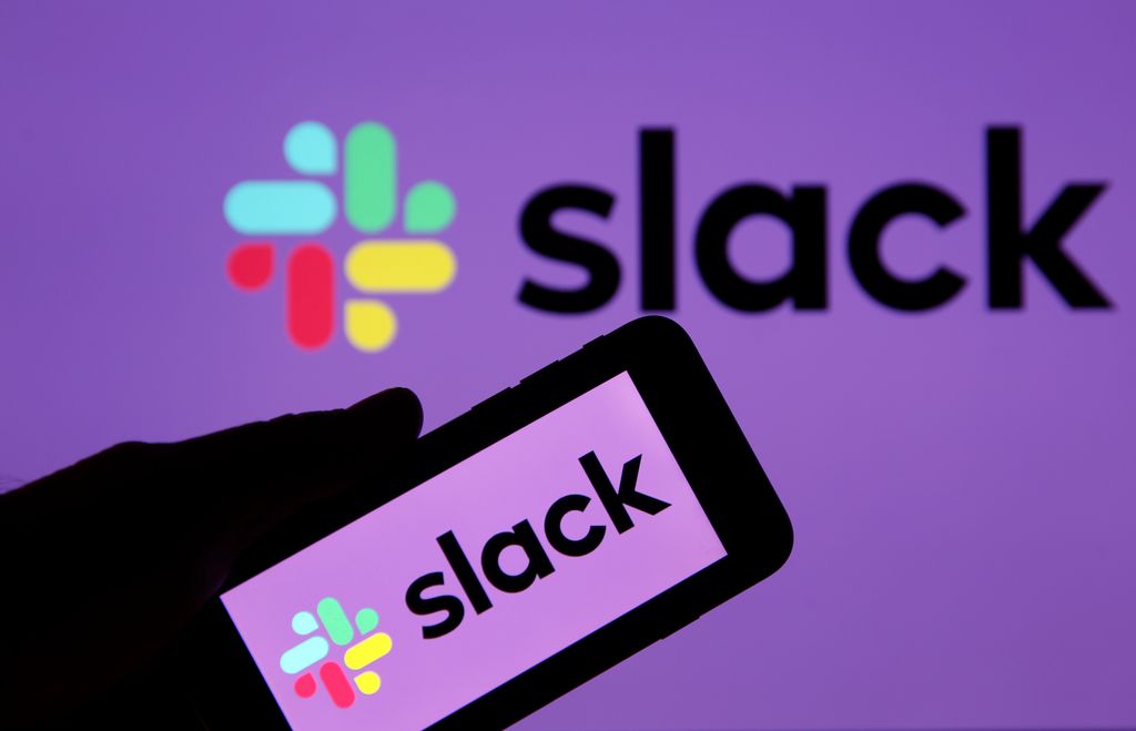 In this photo illustration, the Slack logo is displayed on the screen of an Apple iPhone in front of a computer screen displaying a Slack logo on February 06, 2019 in Paris, France. Slack announced in a statement that it had "confidentially" filed its file with the SEC for an IPO. Launched in 2014 in San Francisco, the US Enterprise Messaging boasts 10 million daily active users in more than 150 countries worldwide.