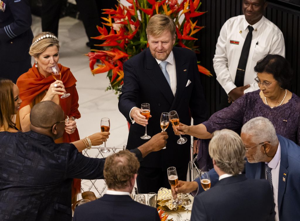 Queen Maxima at reception sipping glass of wine in group of people