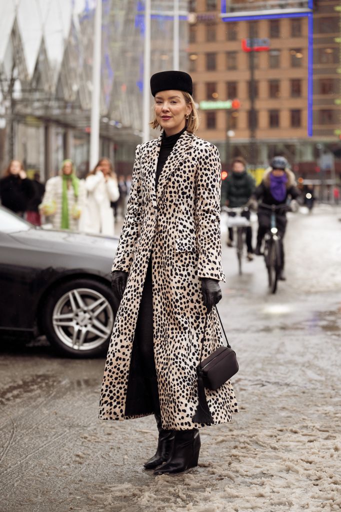Tina Haase wears leopard print long coat, black leather gloves and black hat outside the OperaSport show during Copenhagen Fashion Week AW26,