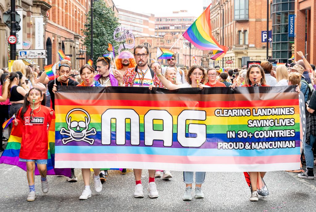 Marchers at Manchester Pride holding a Progress Pride flag