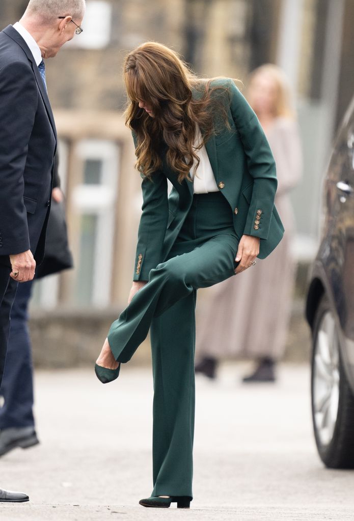 Princess Kate fixes her shoe as she arrives at AW Hainsworth