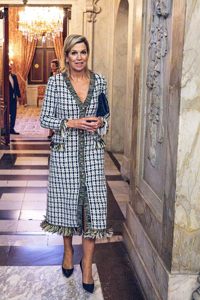 Queen Maxima in a tweed dress and black heels with a bag under her arm