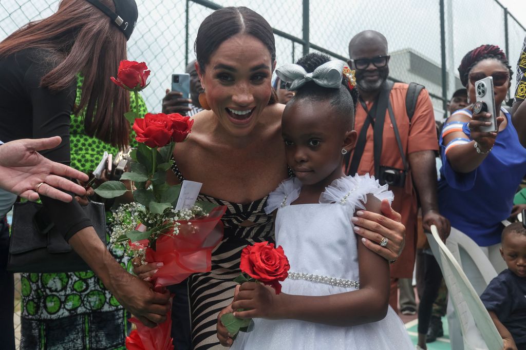 Meghan Markle receives flowers from a girl during a visit to Nigeria Unconquered, a local charity organisation that supports wounded, injured, or sick servicemembers, in Abuja