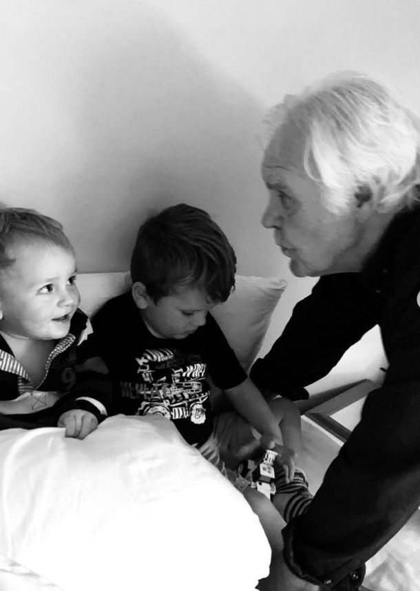 An old man speaking to two young children in bed
