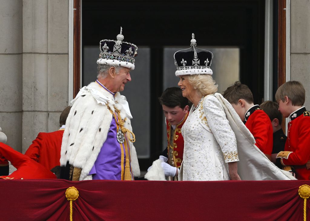 The newly crowned King and Queen beam at one another on the balcony