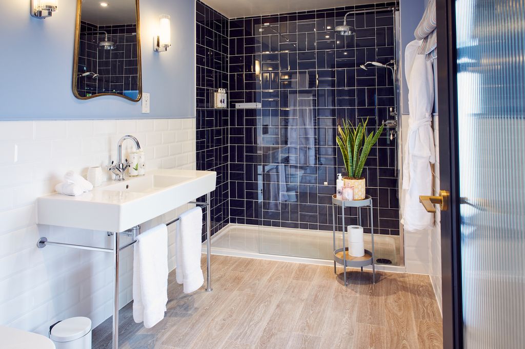 Strood bathroom with large blue-tiled walk-in shower and white sink and white towels
