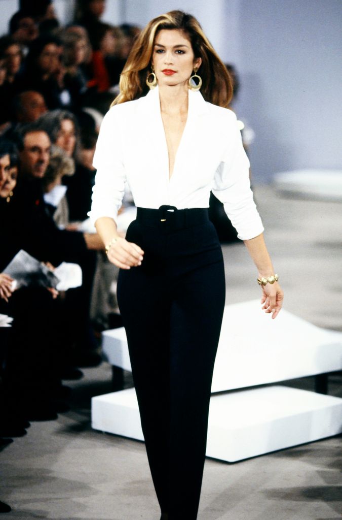 Cindy Crawford walking on the runway in a white shirt