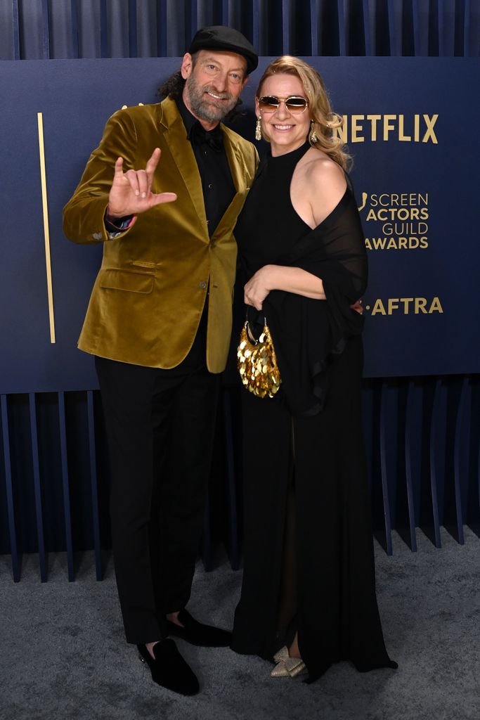 Troy Kotsur in a gold velvet jacket with his wife Deanne Bray