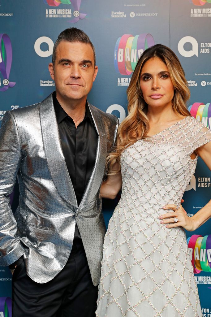 Robbie Williams in a silver tuxedo and Ayda Field in a white dress