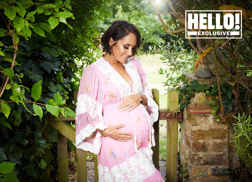Janette Manrara in pink kimono style dress holding baby bump
