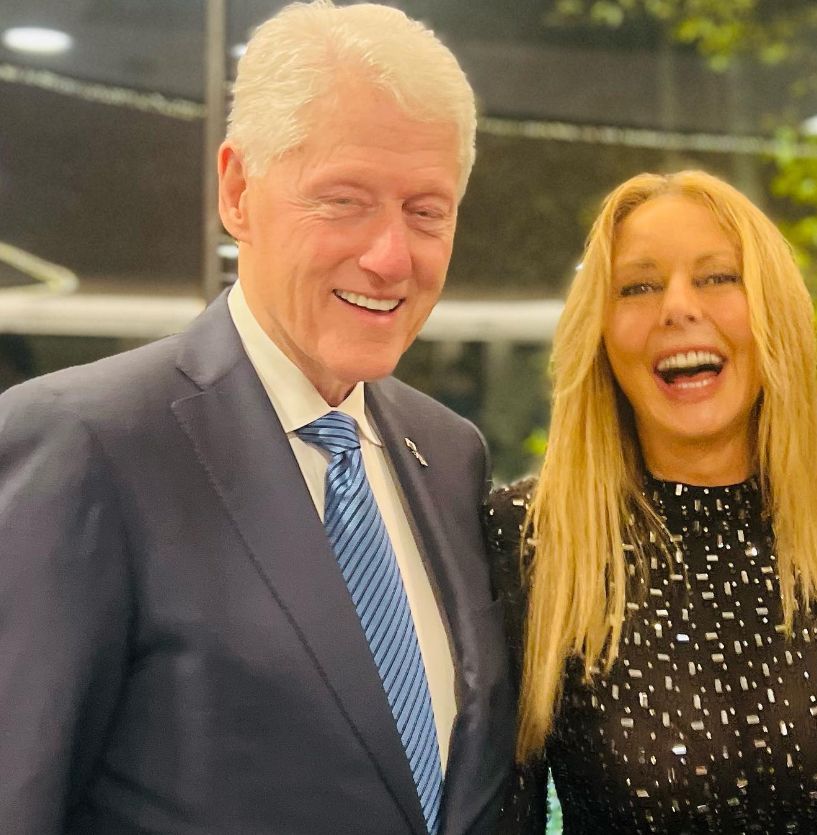 Carol Vorderman in a sheer dress standing with Bill Clinton in a blue suit