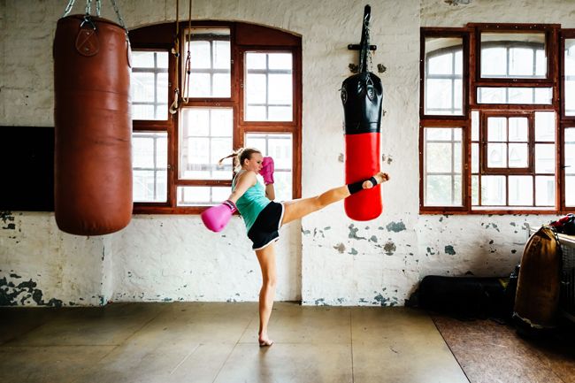Woman kicking a boxing bag in the gym
