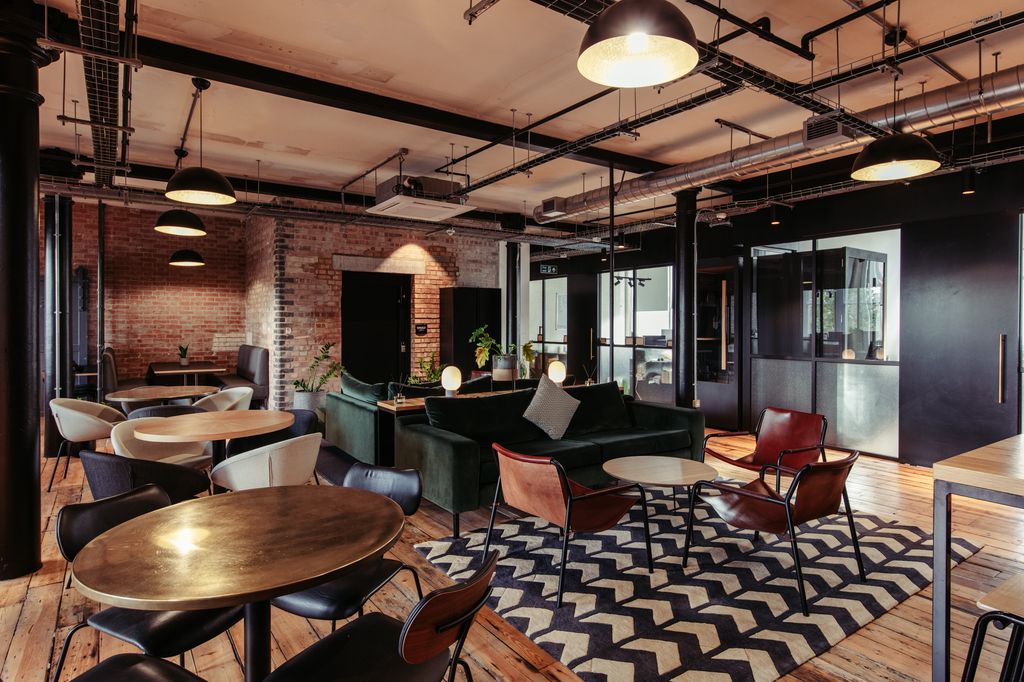 The breakout space in the Ministry with several chairs, tables and patterned carpets