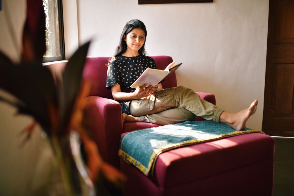 Woman sitting relaxed with legs stretched on a sofa couch and reading a book