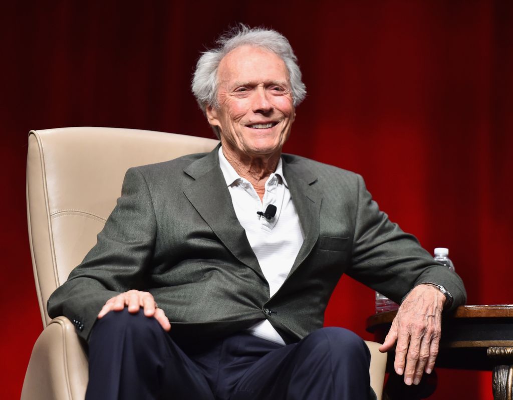 clint eastwood sitting in chair smiling at cinemacon 2015