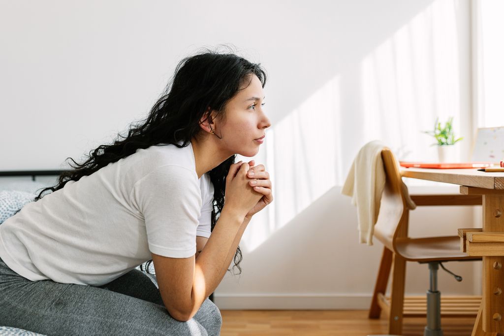 thoughtful woman looking away sitting on bed 