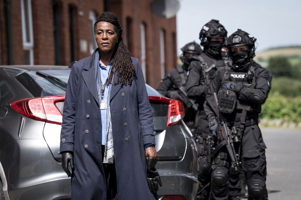 female detective next to armed police officers