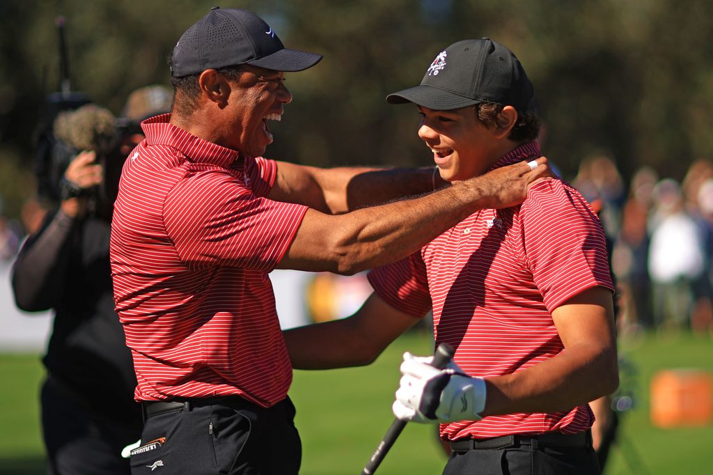 tiger woods embracing son charlie on the golf course