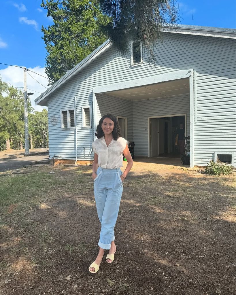 Michelle Keegan standing outside barn in Australia while posing for a photo