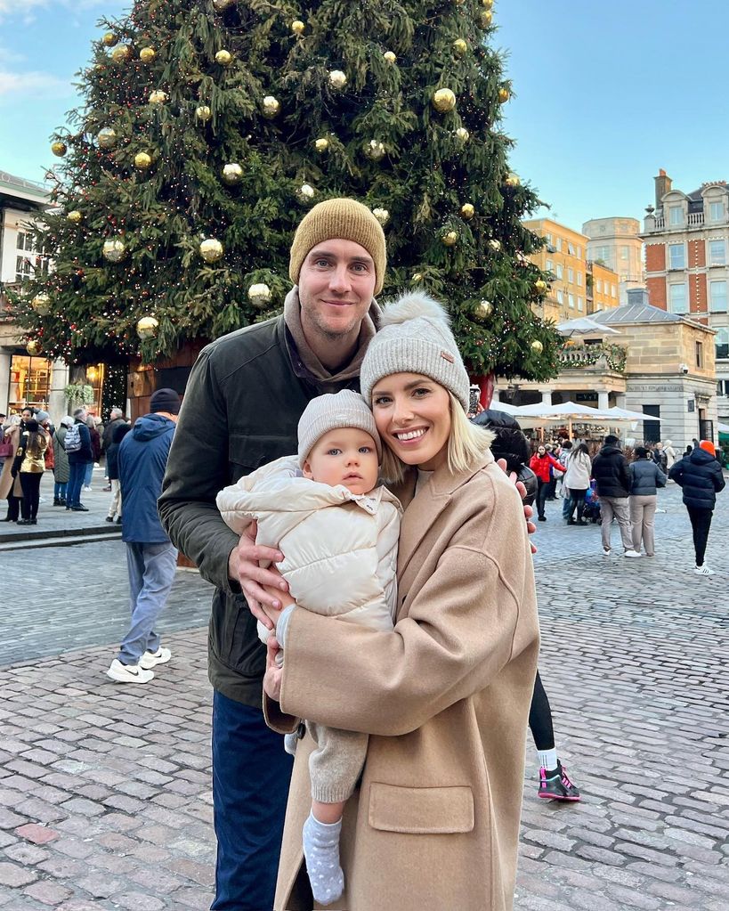 mollie holding annabella with stuart by christmas tree