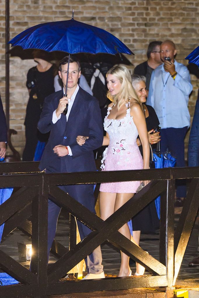 Ivanka Trump arrives at the wedding in a light pink mini dress with 3D floral appliqués, styled with soft blonde waves and white heels.