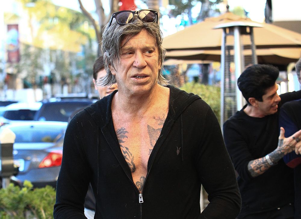 Mickey Rourke walking around in a black zip up jacket 