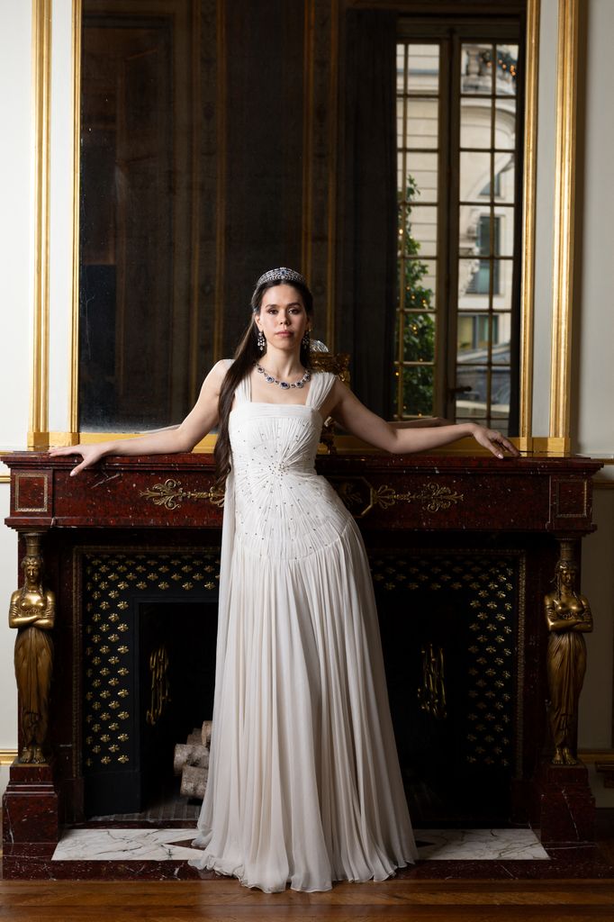 Gabrielle Janssens de Balkany posed in white dress by fireplace