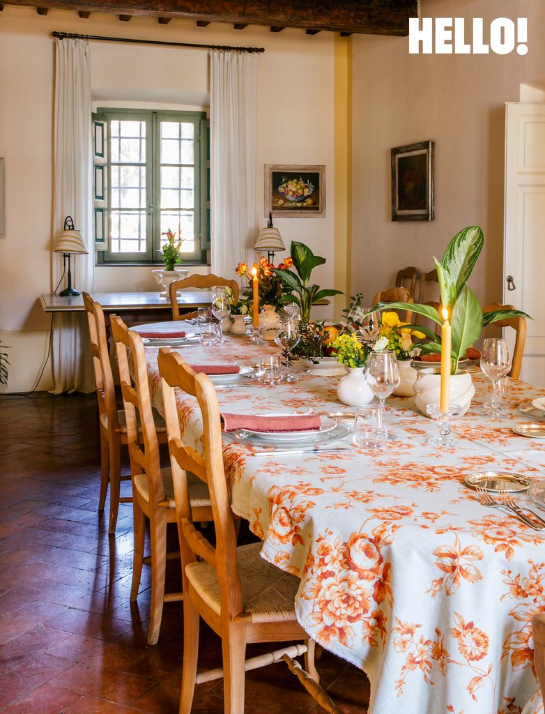 The long dining table is set with family heirloom silver, fresh blooms and a summery floral tablecloth at Villa Talamo
