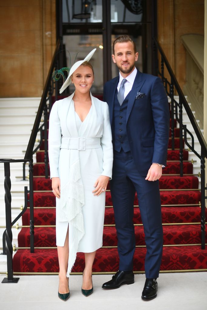 Harry Kane in a blue suit with his wife Kate in a blue dress and hat