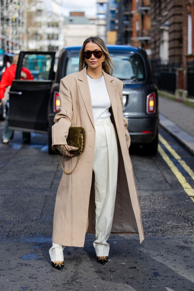 Nadia Phillips wears Gucci gloves, olive teddy bag, beige coat, high waisted white pants, shirt, sunglasses outside Bora Aksu during London Fashion Week February 2024 on February 16, 2024 in London, England. (Photo by Christian Vierig/Getty Images)