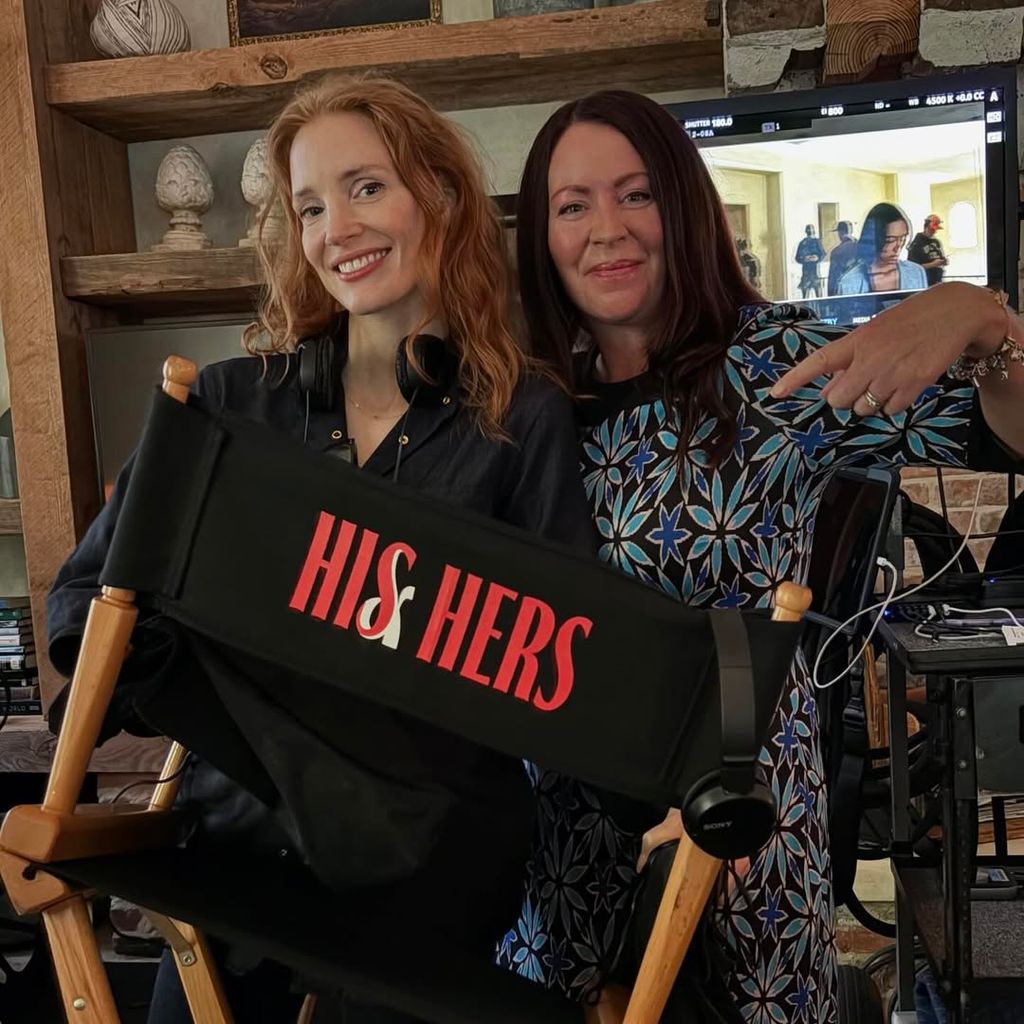 Two women pose with a movie set chair