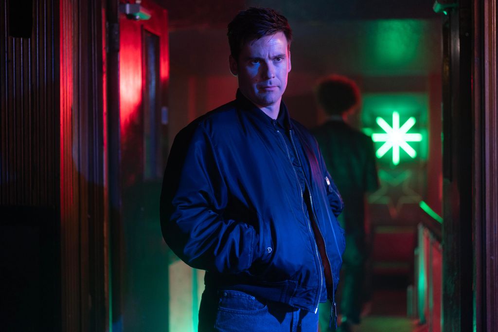 man in dark clothing standing in dimly-lit room
