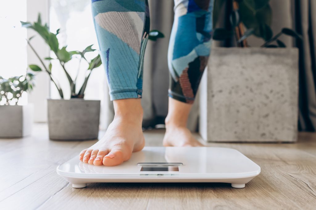 Close-up of bare feet stepping onto a digital scale, symbolizing health, fitness, and mindfulness in a modern home setting