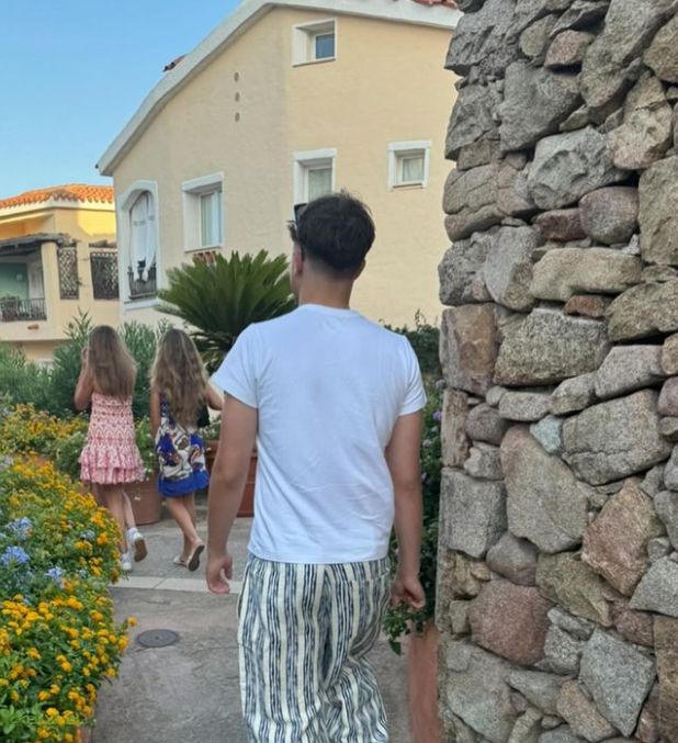 A teenage boy walking behind two girls, his back is to the camera