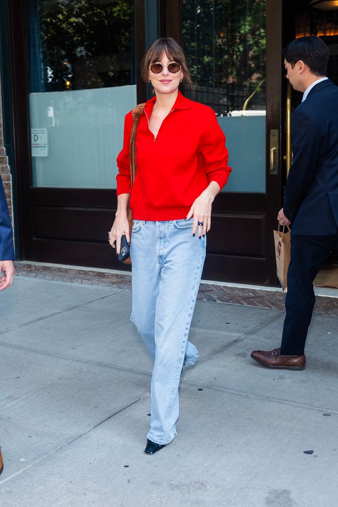 Dakota walking in a red top and jeans 