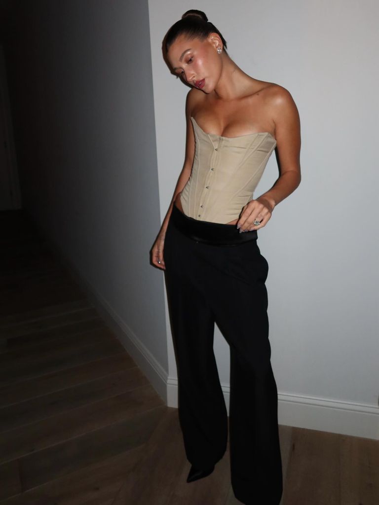 Hailey Bieber in her stunning corset, teamed with black trousers and silver jewellery. She wears her hair in a slick back bun and opts for minimal (yet seriously sparkling) jewellery.